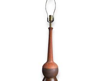 May include: A tall, mid-century modern table lamp with a brown and orange ceramic body. The lamp features a slender, ribbed neck and a rounded base. The lamp has a brass-colored neck and a metal base.