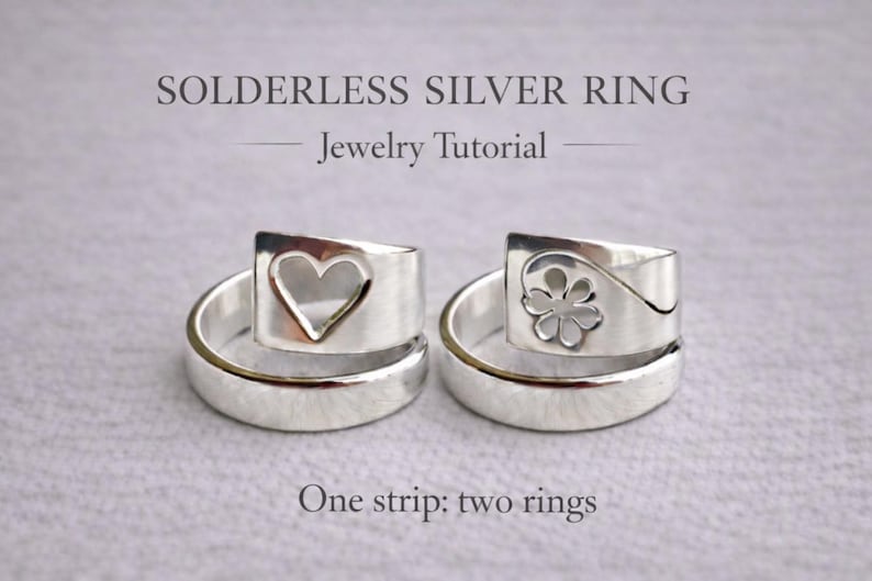 Op de afbeelding: Twee zilveren ringen met unieke ontwerpen. E&eacute;n ring heeft een hartvormige uitsparing, de andere een bloem. De ringen maken deel uit van een sieraden tutorial, zoals aangegeven door de tekst "Solderless Silver Ring - Jewelry Tutorial". Gemaakt van &eacute;&eacute;n strip.