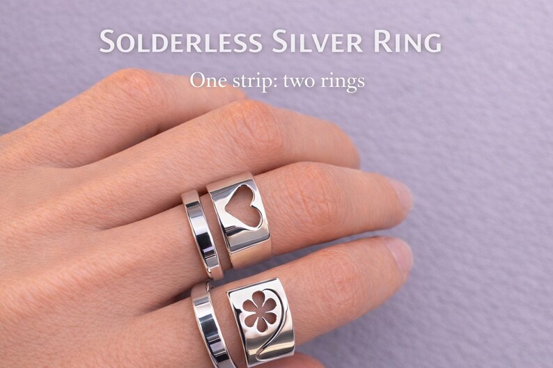 Op de afbeelding: Twee zilveren ringen worden op een hand getoond. De bovenste ring heeft een hartvormige uitsparing en de onderste ring heeft een bloemvormige uitsparing. De tekst "Solderless Silver Ring" en "One strip: two rings" is zichtbaar.