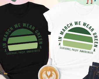 May include: Two t-shirts, one black and one white, with a green sunset graphic and the text "In March We Wear Green & Cerebral Palsy Awareness".