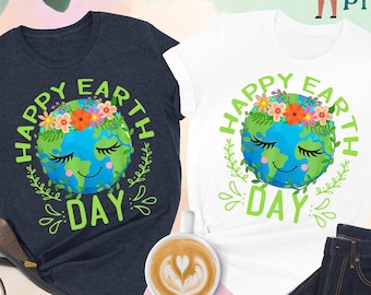 May include: Two t-shirts with a graphic of a smiling cartoon Earth wearing a flower crown. The text "Happy Earth Day" is written in green around the Earth. One shirt is heather navy and the other is white.