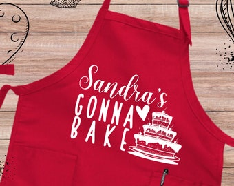 May include: Red kitchen apron with a white pocket and the text "Sandra's Gonna Bake" with a heart and a cake illustration.