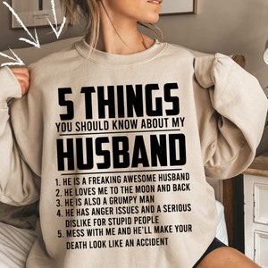 May include: A beige sweatshirt with black text that reads "5 Things You Should Know About My Husband" and lists five reasons why.