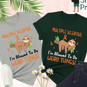 May include: Two t-shirts with a sloth design and the text "Multiple Sclerosis I'm Allowed To Do Weird Things!" One shirt is gray and the other is green.
