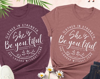 Może przedstawiać: Dwie koszulki z melanżu, jedna bordowa i jedna w kolorze mauve, z napisem "She is Be.you.tiful" w okrągłym wzorze. Koszulki są połączone z białymi trampkami i ciemnoniebieskimi dżinsami. Widoczny jest również napis "Fast Shirt Print".