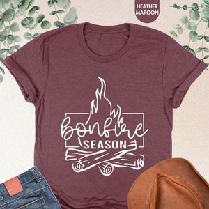 a t - shirt that says bonfire season next to a cowboy hat