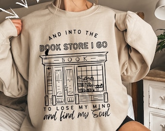 May include: A beige sweatshirt with a black graphic of a bookstore with the text "And into the book store I go to lose my mind and find my soul".