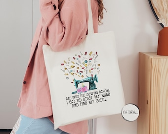 May include: A white tote bag with a colorful illustration of a sewing machine and sewing supplies. The text on the bag reads "And into the sewing room I go to lose my mind and find my soul."
