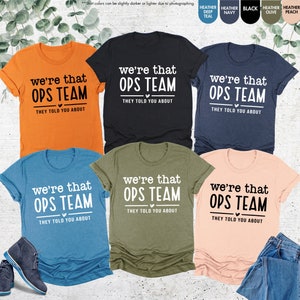 May include: Six t-shirts in different colors with the text "we're that OPS TEAM they told you about" printed on the front. The t-shirts are available in orange, black, navy blue, heather teal, olive green, and peach.