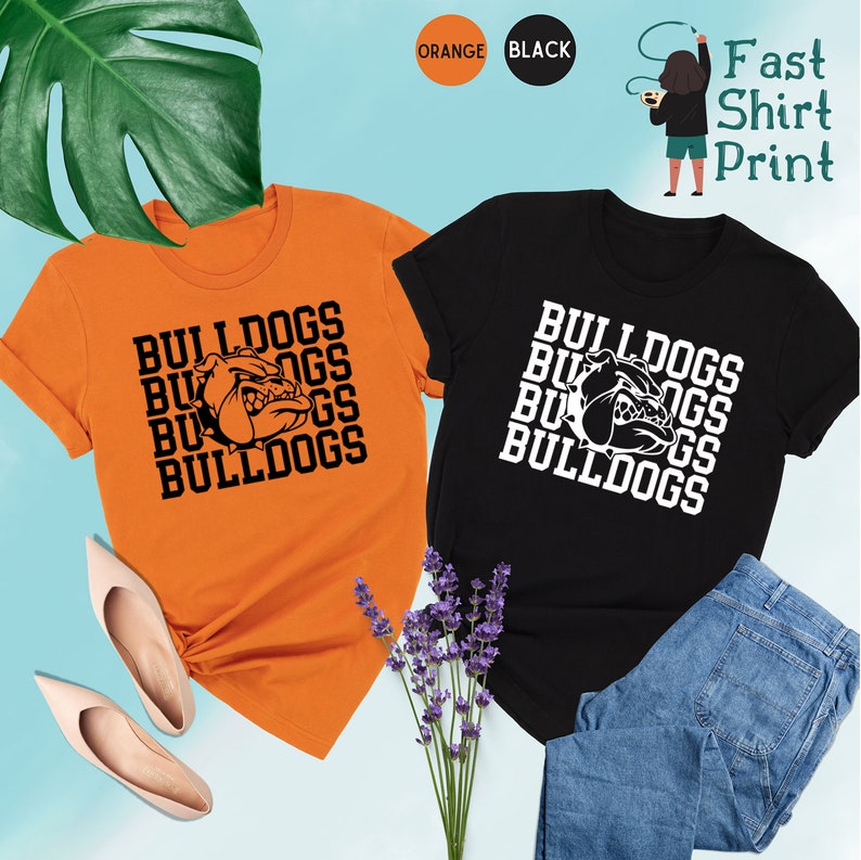 May include: Two t-shirts, one orange and one black, with the word "Bulldogs" repeated four times in a stacked pattern. A bulldog head graphic is centered in the middle of each shirt.
