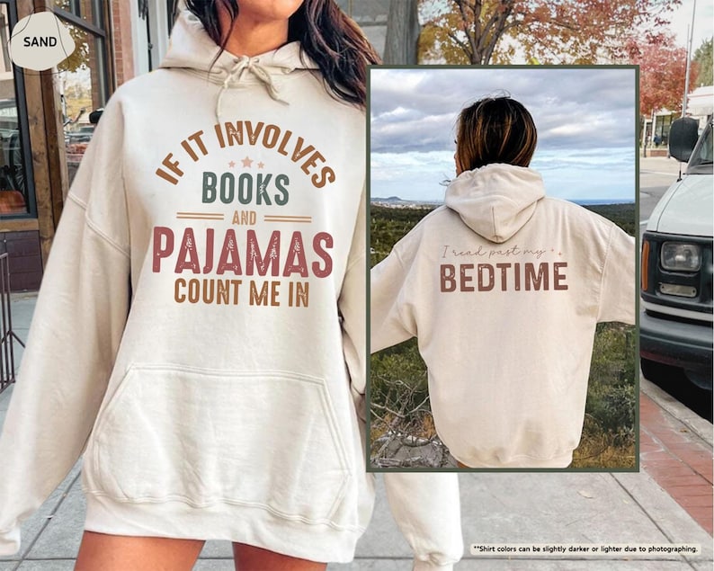 Puede incluir: Una sudadera con capucha de color crema con el texto "If it involves books and pajamas count me in" en letras marrones y verdes. La parte posterior de la sudadera con capucha tiene el texto "I read past my bedtime" en letras marrones.