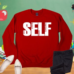 May include: Red long-sleeve sweatshirt with the word "SELF" in white letters. The letters are made up of the words "LOVE", "RESPECT", "WORTH", and "CONFIDENCE".