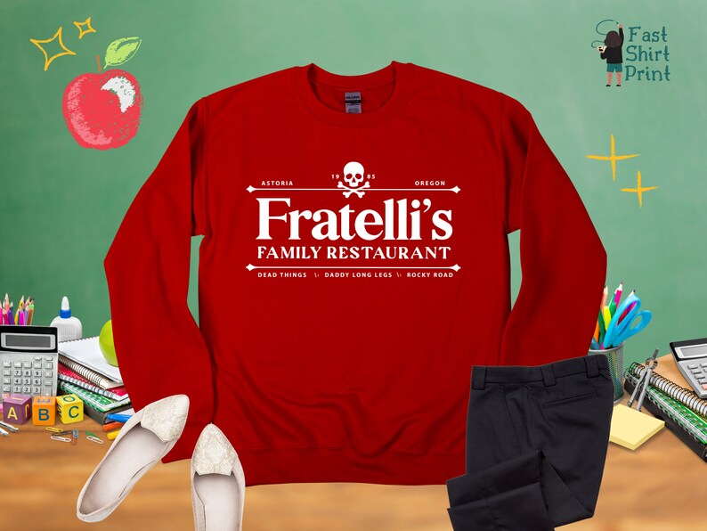 May include: Red long-sleeved sweatshirt with a white graphic of a skull and crossbones and the text "Fratelli's Family Restaurant" with the words "Astoria, Oregon" and "Dead Things, Daddy Long Legs, Rocky Road" underneath.