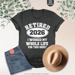 Puede incluir: Camiseta gris oscuro jaspeado con el texto "RETIRED 2026 I WORKED MY WHOLE LIFE FOR THIS SHIRT". Se combina con vaqueros azules y un sombrero beige. El color de la camiseta es gris oscuro jaspeado.