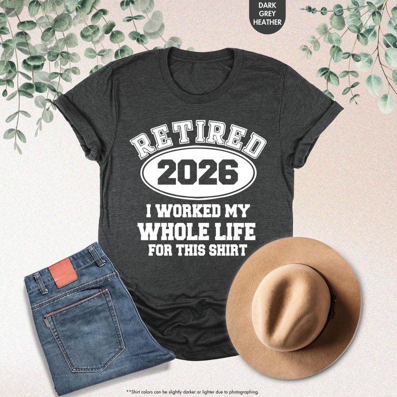 Puede incluir: Camiseta gris oscuro jaspeado con el texto "RETIRED 2026 I WORKED MY WHOLE LIFE FOR THIS SHIRT". Se combina con vaqueros azules y un sombrero beige. El color de la camiseta es gris oscuro jaspeado.