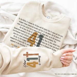 May include: A beige sweatshirt with a brown and black graphic design featuring the number 41 and the text "Your 41 is coming". The text "In the Bible, it rained for 40 days and 40 nights, Day 41 came and the rain stopped, Moses committed murder and hid in the desert for 40 years, 41 came, and God called him to rescue Israel, Moses went up on the mountain for 40 days. On day 41, he received the Ten Commandments, The Israelites wandered in the wilderness for 40 years, Year 41, they walked into the Promised Land, Goliath, taunted Israel for 40 days, Day 41 came, and David slew him, Jonah preached a message of repentance to Niveneh for 40 days. On day 41, God stopped his plan to destroy the tempted for 40 days. Day 41, and the appeared to his disciples for the THE RAIN W" is printed on the sweatshirt.