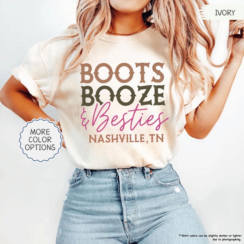 Pu&ograve; includere: T-shirt color avorio con le parole "BOOTS BOOZE & Besties" in lettere marroni, verde oliva e rosa. Il testo "NASHVILLE, TN" &egrave; in basso. Un pulsante a sinistra dice "MORE COLOR OPTIONS".