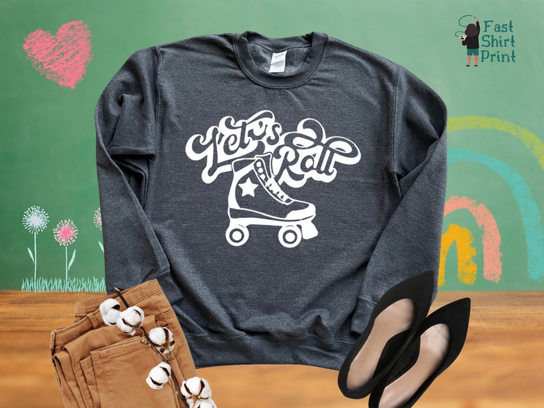 May include: A dark gray sweatshirt with the text "Let's Roll" in white, featuring a white roller skate with a star on the side.