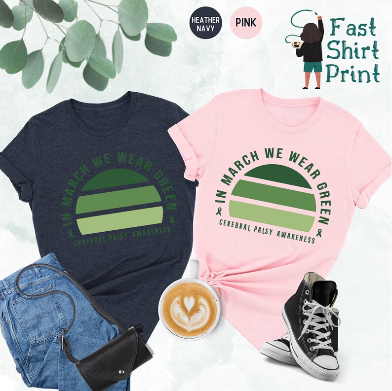 May include: Two t-shirts with a green sunset graphic and the text "In March We Wear Green" and "Cerebral Palsy Awareness". One shirt is heather navy and the other is pink.
