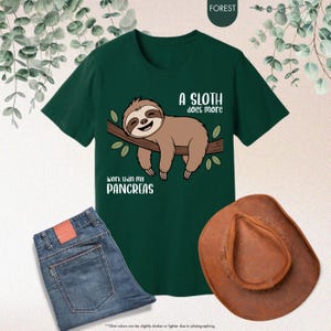 K&ouml;nnte beinhalten: Dunkelgr&uuml;nes T-Shirt mit einem Faultier-Motiv und dem Text "A sloth does more work than my pancreas." Das Bild zeigt auch eine blaue Jeans und einen braunen Cowboyhut.