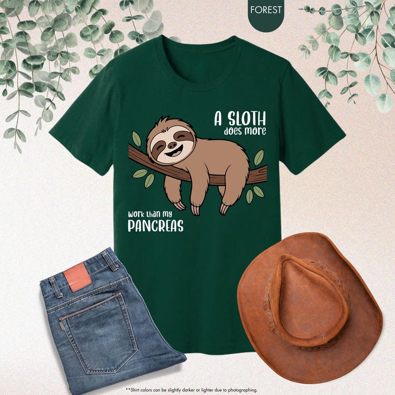 K&ouml;nnte beinhalten: Dunkelgr&uuml;nes T-Shirt mit einem Faultier-Motiv und dem Text "A sloth does more work than my pancreas." Das Bild zeigt auch eine blaue Jeans und einen braunen Cowboyhut.