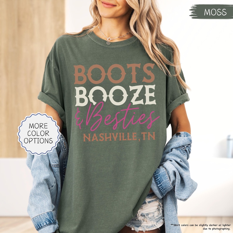 Pu&ograve; includere: T-shirt verde muschio con la scritta "BOOTS BOOZE & Besties" in marrone, bianco e rosa. Il testo "NASHVILLE, TN" &egrave; stampato sotto. La maglietta ha le maniche arrotolate ed &egrave; abbinata a una giacca di jeans.