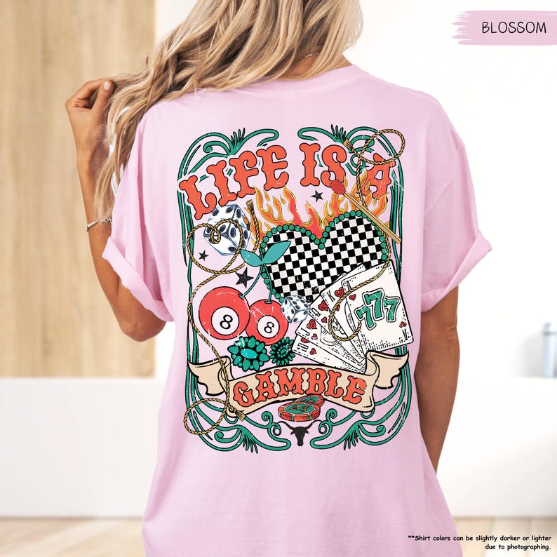 Puede incluir: Camiseta rosa con un dise&ntilde;o gr&aacute;fico de un coraz&oacute;n con llamas, cerezas, dados, cartas de juego y el texto "Life is a Gamble".