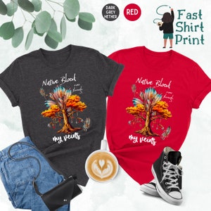 May include: Two t-shirts with a Native American design. The design features a tree with feathers and the text "Native Blood runs through my veins". One shirt is dark heather grey and the other is red.