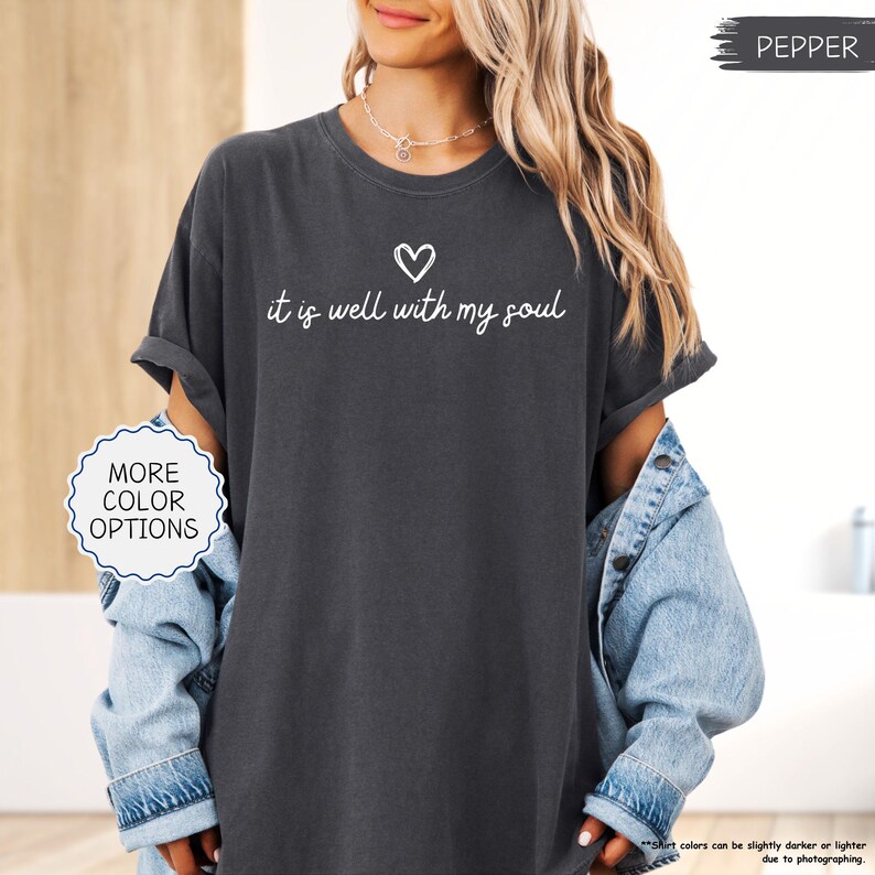 K&ouml;nnte beinhalten: Pfefferfarbenes T-Shirt mit dem Schriftzug "it is well with my soul" in wei&szlig;er Schrift, begleitet von einem Herzsymbol. Das Shirt hat hochgekrempelte &Auml;rmel und geh&ouml;rt zu einer Kollektion mit weiteren Farboptionen.