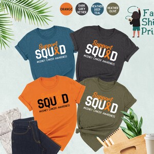 May include: Five t-shirts in different colors with the text "Support Squad" and a kidney cancer awareness ribbon. The text "#Kidney Cancer Awareness" is below the ribbon. The t-shirts are in orange, dark heather grey, heather deep teal, heather olive, and blue.