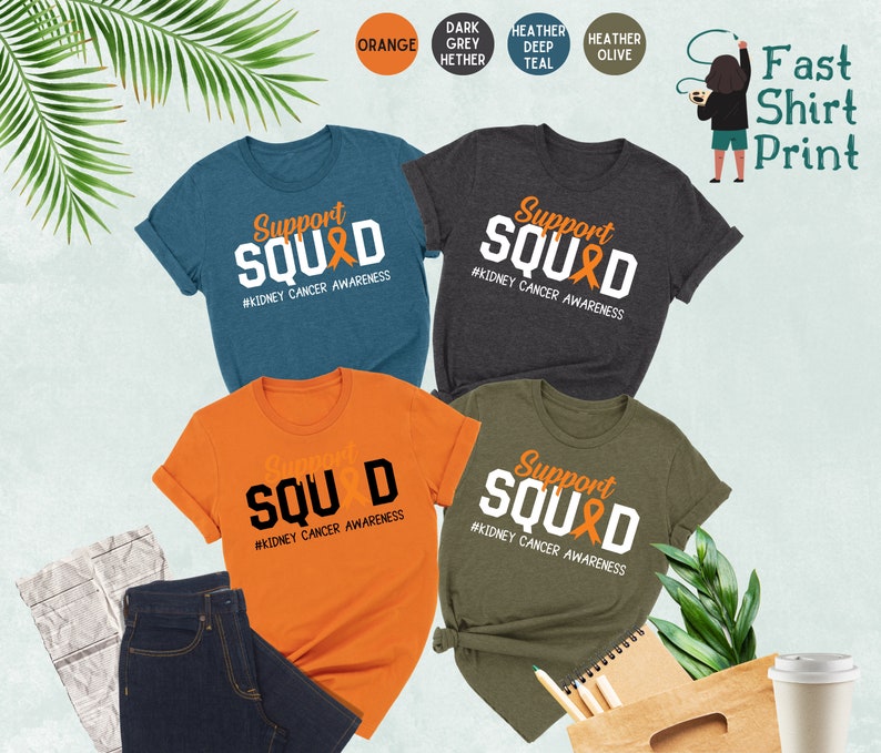 May include: Five t-shirts in different colors with the text "Support Squad" and a kidney cancer awareness ribbon. The text "#Kidney Cancer Awareness" is below the ribbon. The t-shirts are in orange, dark heather grey, heather deep teal, heather olive, and blue.