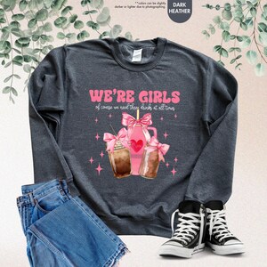 K&ouml;nnte beinhalten: Dunkelgrauer Sweatshirt mit dem Text "WE'RE GIRLS of course we need three drinks at all times" und einer Grafik von drei pinkfarbenen, mit Schleifen verzierten Eiskaffees.