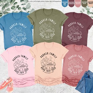 May include: A collection of t-shirts in various colours, including blue, green, pink, peach, and maroon. Each shirt features a mountain and camper graphic with the text "PARKER FAMILY ROAD TRIP 2026 MY ADVENTUROUS TRIBE."