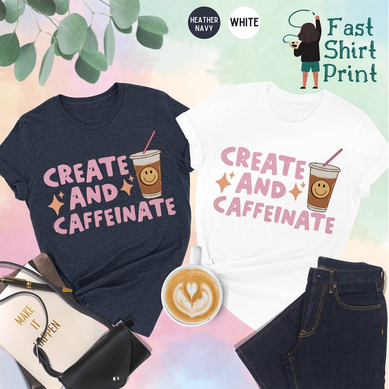 May include: Two t-shirts with the text "Create and Caffeinate" and a cartoon coffee cup with a smiley face. The t-shirts are in heather navy and white.