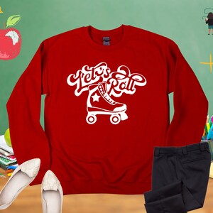 May include: Red long-sleeve sweatshirt with white text that says "Let's Roll" and a white roller skate graphic.