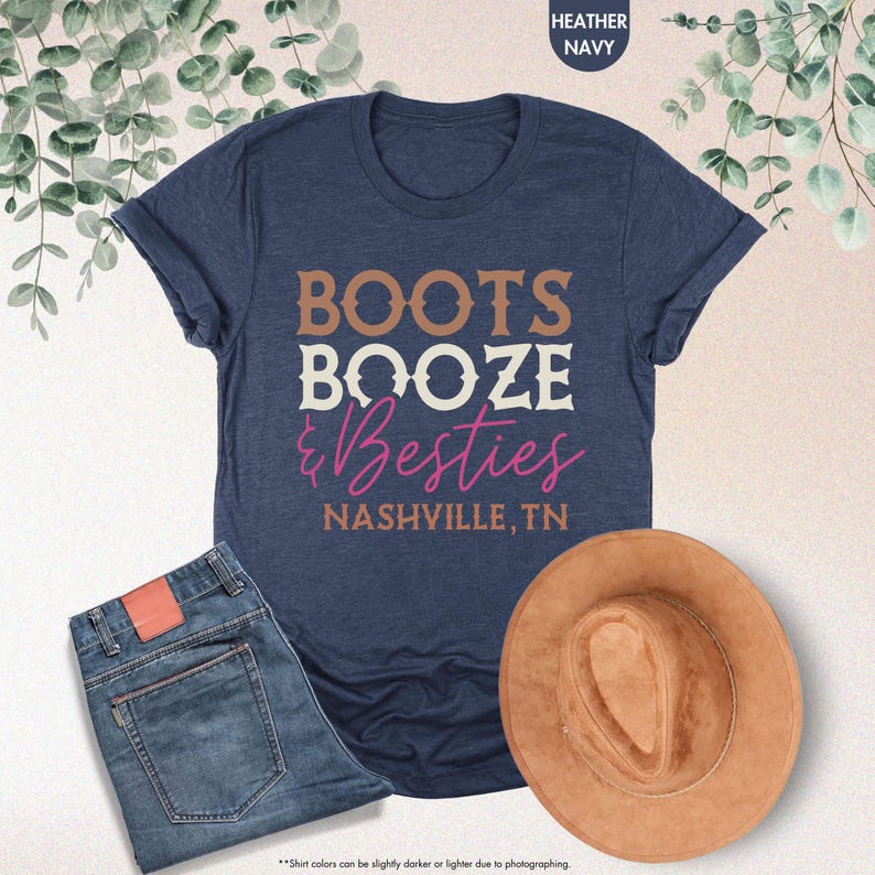 Pu&ograve; includere: Una maglietta blu navy con le parole "BOOTS BOOZE & Besties NASHVILLE, TN" in lettere marroni, bianche e rosa. La maglietta &egrave; abbinata a jeans blu e un cappello da cowboy marrone.