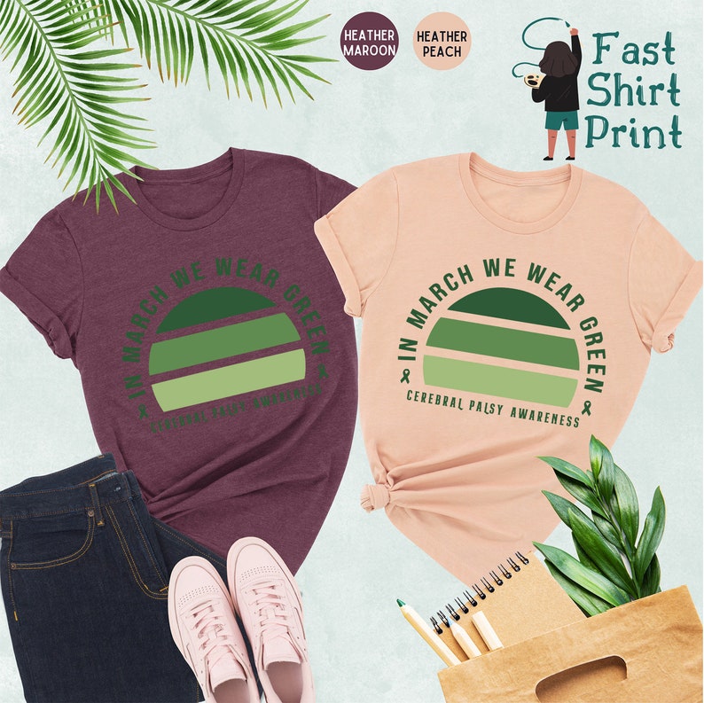 May include: Two t-shirts with a green sunset graphic and the text "In March We Wear Green & Cerebral Palsy Awareness". The shirts are available in heather maroon and heather peach.