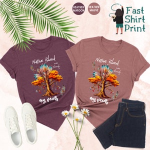 May include: Two heather colored t-shirts with a Native American inspired tree design. The text on the shirts reads "Native Blood runs through my veins".