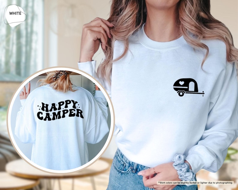 May include: White sweatshirt with a black camper graphic on the front and the words "HAPPY CAMPER" on the back. The camper graphic includes a heart. A casual, long-sleeved top for camping enthusiasts.