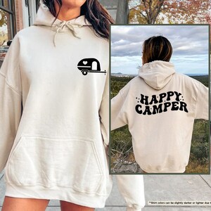 a woman wearing a white happy camper hoodie
