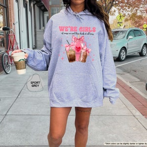 a woman walking down a sidewalk holding a cup of coffee