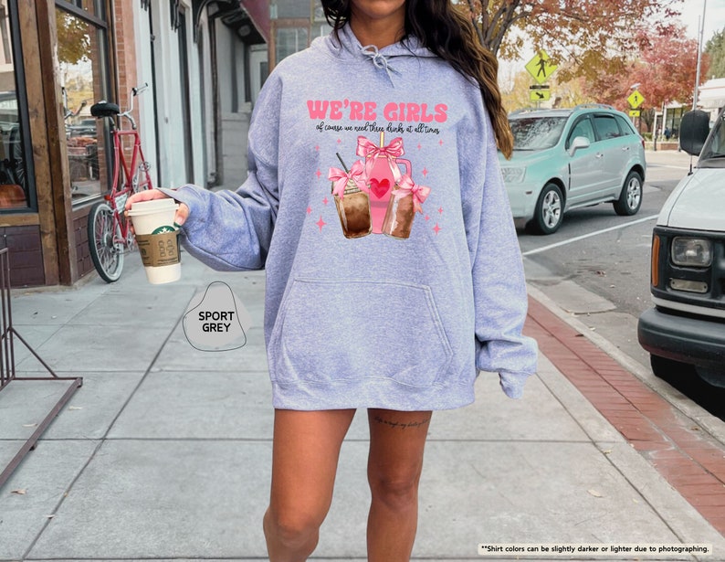 a woman walking down a sidewalk holding a cup of coffee