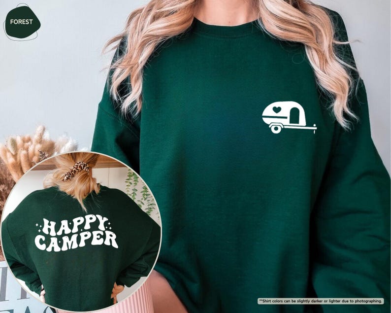 May include: Forest green sweatshirt with a white graphic of a camper trailer and a heart. The back of the sweatshirt has the words "HAPPY CAMPER" in white. The sweatshirt is a crew neck style.