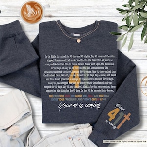 May include: Dark heather grey sweatshirt with a colourful graphic design featuring the text "Your 41 is coming" and "Your 41 is coming". The graphic design includes a rainbow colour scheme and a cross.