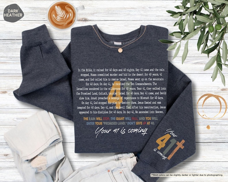 May include: Dark heather grey sweatshirt with a colourful graphic design featuring the text "Your 41 is coming" and "Your 41 is coming". The graphic design includes a rainbow colour scheme and a cross.