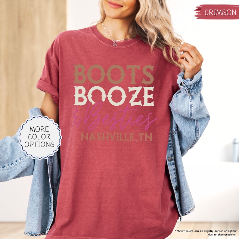 Pu&ograve; includere: T-shirt color cremisi con le parole "BOOTS BOOZE &ties" in un design a strati. Il testo "NASHVILLE, TN" &egrave; in basso. La maglietta ha una vestibilit&agrave; ampia e maniche arrotolate. Un bottone sul lato sinistro dice "MORE COLOR OPTIONS".
