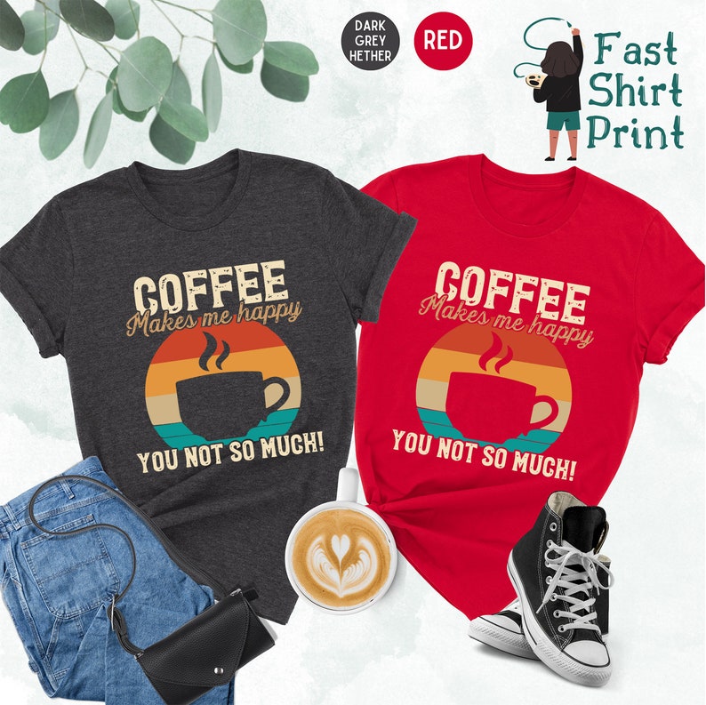 May include: Two t-shirts with a vintage-style graphic of a coffee cup and the text "Coffee Makes Me Happy You Not So Much!" One shirt is dark heather grey and the other is red.