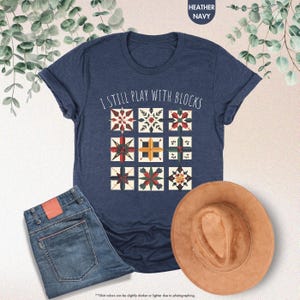 May include: A navy blue t-shirt with the text "I still play with blocks" and a graphic of colorful quilt blocks.