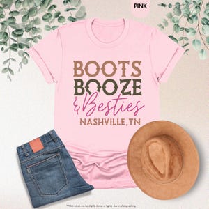 Pu&ograve; includere: Una maglietta rosa con le parole "BOOTS, BOOZE, & Besties" e "NASHVILLE, TN" stampate sopra. La maglietta &egrave; abbinata a jeans blu e un cappello da cowboy marrone. Il colore della maglietta &egrave; rosa.