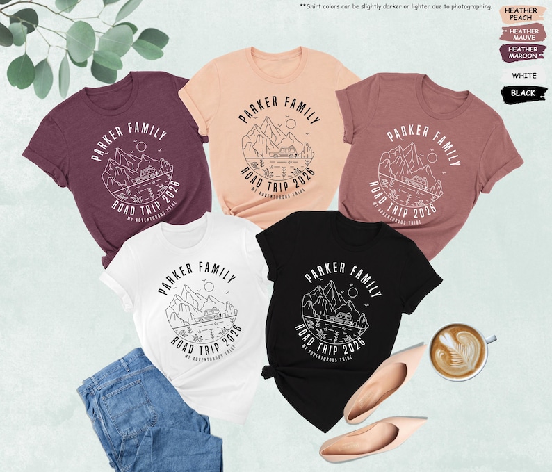 May include: Several t-shirts in shades of maroon, peach, white, and black, each displaying the text "PARKER FAMILY ROAD TRIP 2026" within a mountain and lake design. The image also includes a pair of jeans, shoes, and a coffee cup. Measurements are not applicable.